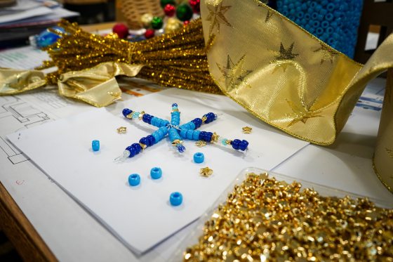 A craft kit featuring a blue beaded star and gold ribbon. 