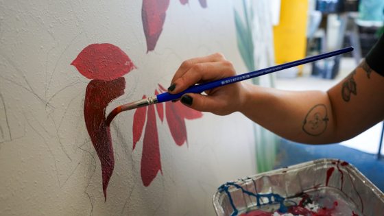 A person painting poinsettia leaves onto a white background.