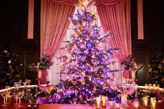 A pink and purple lit and decorated Christmas tree inside a circular bar.