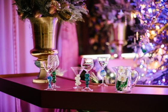 A holiday bar scene with hand-blown glass drinkware on top of the bar.