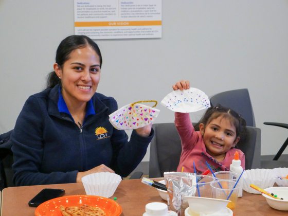 A staff member at LCH helping a child make a Christmas ornament.