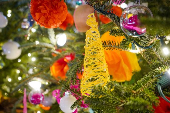 A close up of a yellow cone shaped ornament hanging on a Christmas tree.