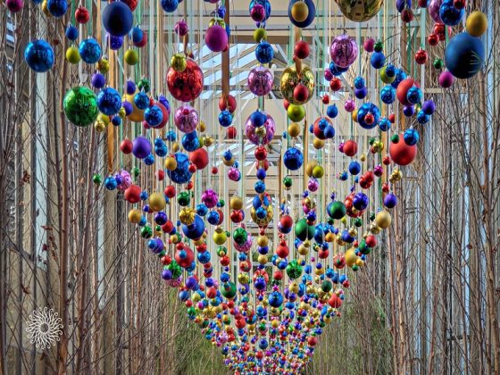 Christmas ball ornaments in a variety of colors hanging in rows from the ceiling. 
