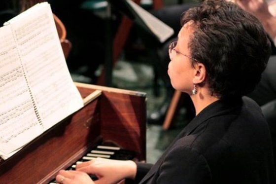 A person seated at an organ playing the keys.