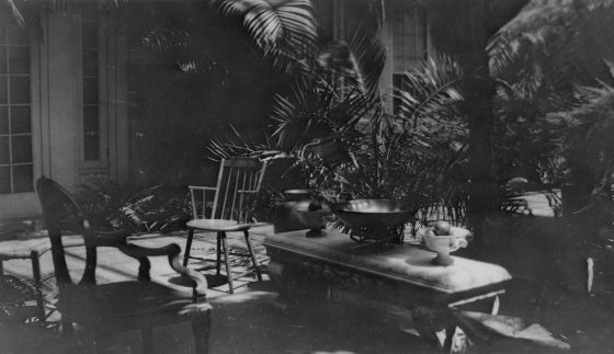 A black and white image of the interior of the Peirce du Pont House at Longwood Gardens, featuring a white marble bench and chairs.