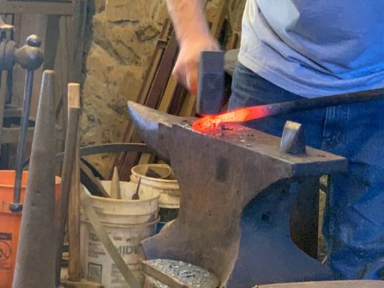 A person using a hammer to shaped heated iron. 