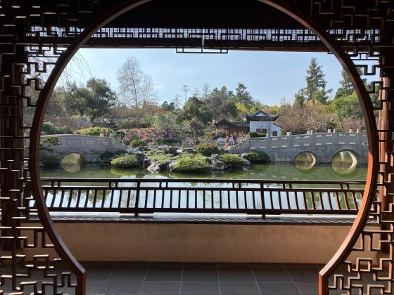 A circular archway overlooking a pond and Chinese inspired garden.