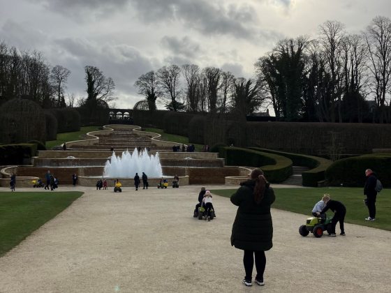 The Alnwick Garden, featuring a fountain in the center, topiary along the sides, and a stone staircase in the center.