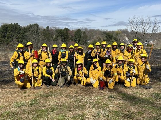 A fire team in yellow protective gear assembled for a group photo.