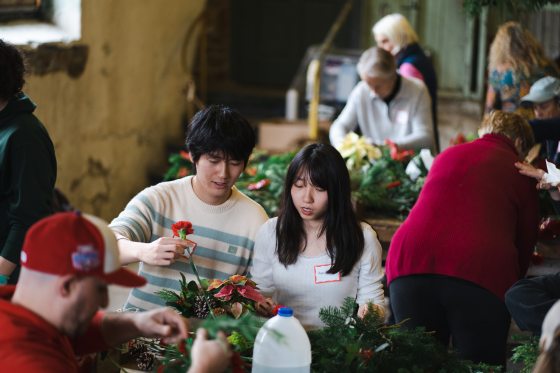 Two people sitting next to each other creating a floral arrangement.
