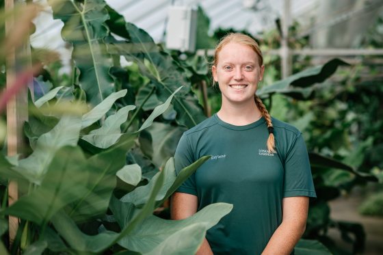 A person standing among plant foliage smiling at the camera.