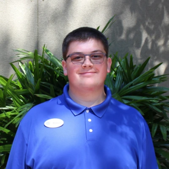 Portrait of person with short black hair and ruddy complexion, wearing glasses and a bright blue polo shirt.