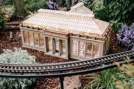 A model of the Longwood Gardens Main Conservatory sitting in an outdoor model train display.