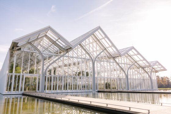 A glass conservatory, with peaked roof lines, surrounded by water, at Longwood Gardens.