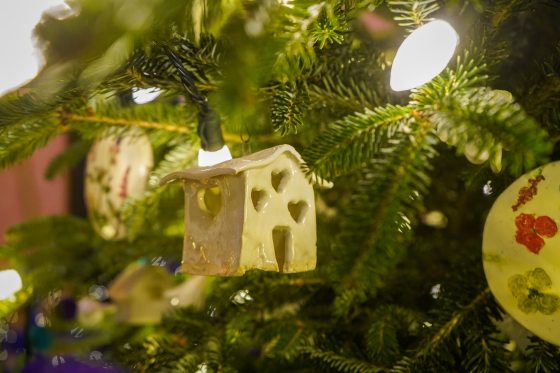Mini ceramic birdhouse ornaments hanging on a Christmas tree.