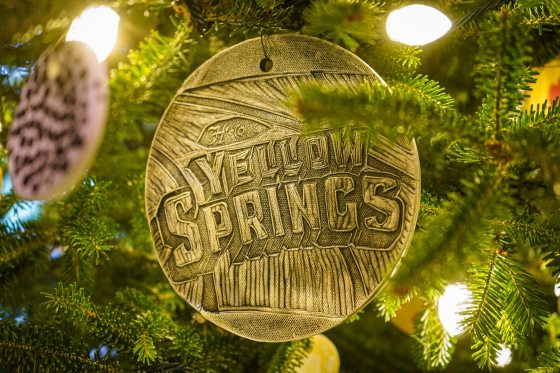 A circular ornament that reads "Yellow Springs" hanging on a Christmas tree.