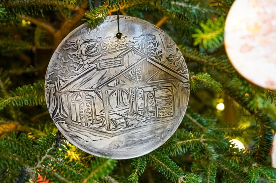 A circular ornament in silver featuring an etching of a covered bridge.