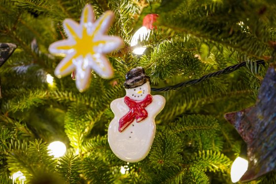 A snowman made out of clay hanging on a Christmas tree.
