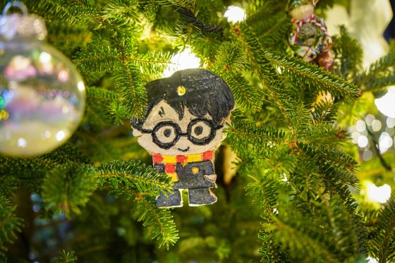 A handmade ornament painted to look like Harry Potter, hanging on a Christmas tree.