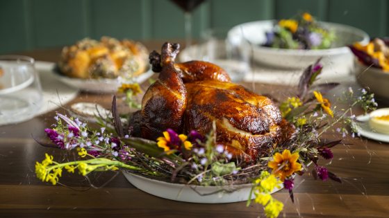 A roasted chicked laying on a bed of wild flowers. 