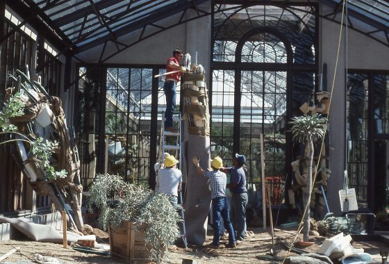 Construction of a garden at Longwood Gardens, with people installing tall cacti and palms.