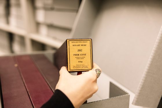 A person's hand, holding an organ roll up for display.