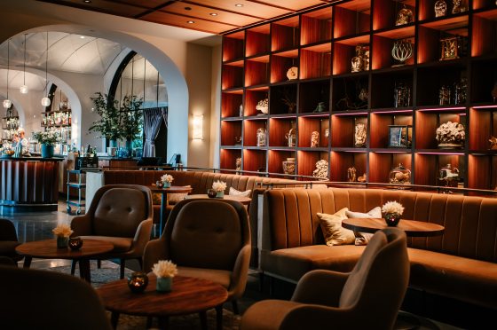 A lounge inside a mid-century styled restaurant with shelving featuring antique items from Longwood Gardens.
