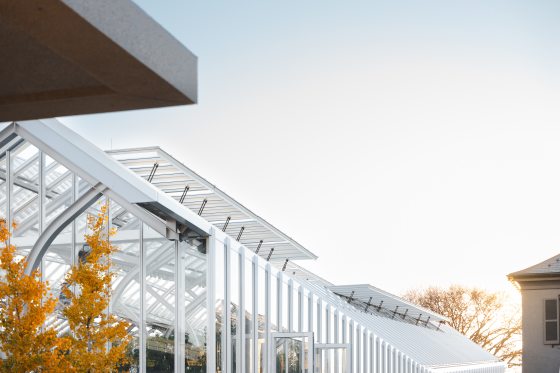 The roof line of a glasshouse, plant conservatory, featuring white steel and glass panels.