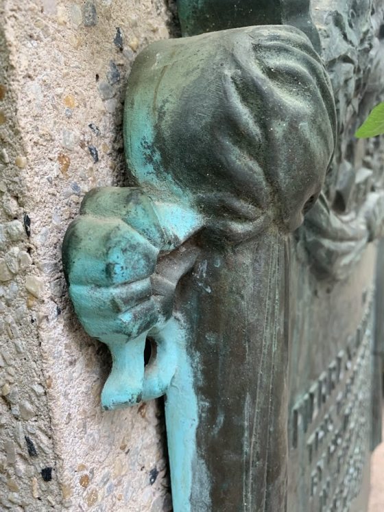 The side of a large bronze plaque with patina on the edge.