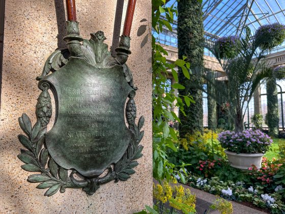 a large bronze plaque hanging on a column in the Longwood Gardens conservatory.