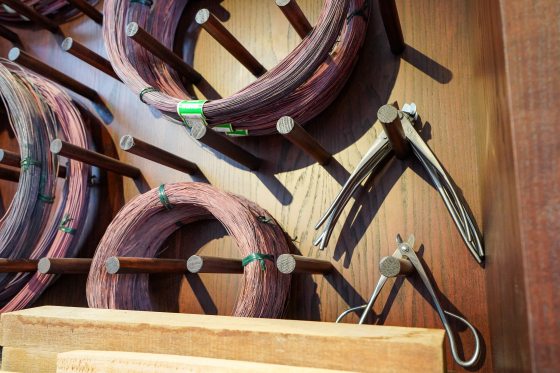 Rolls of thin wire and wire cutters hanging from pegs on a wall.