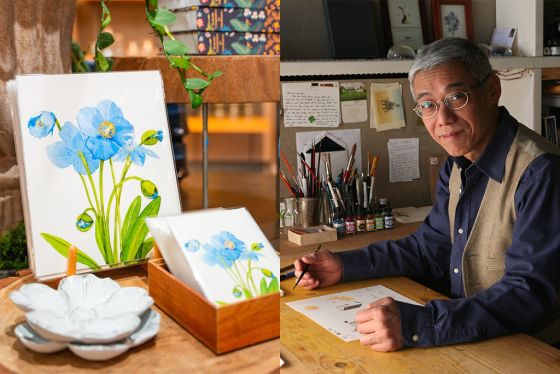 A person sitting at a desk creating art pieces featuring blue poppies.