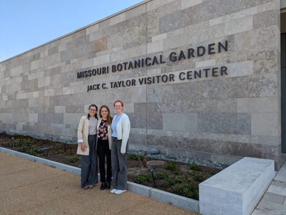 Three people standing in front a stone wall, with black lettering that reads "Missouri Botanical Garden, Jack C. Taylor Visitor Center."
