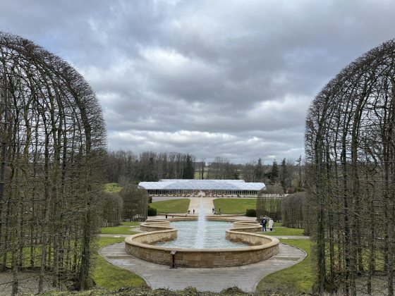 The Alnwick Garden, featuring a fountain in the center, topiary along the sides, and a stone staircase in the center.