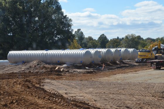 Six large silver tubular-shaped rain tanks in a construction site.