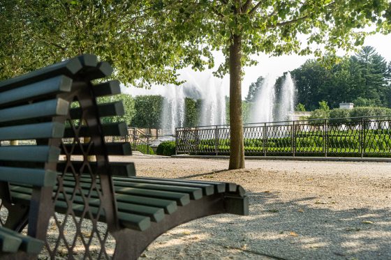 A partial view of a bench overlooking fountains at Longwood Gardens.