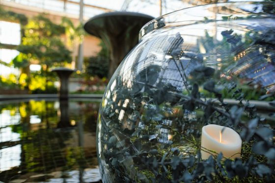 A close up of a glass bowl with floral and luminaries. 