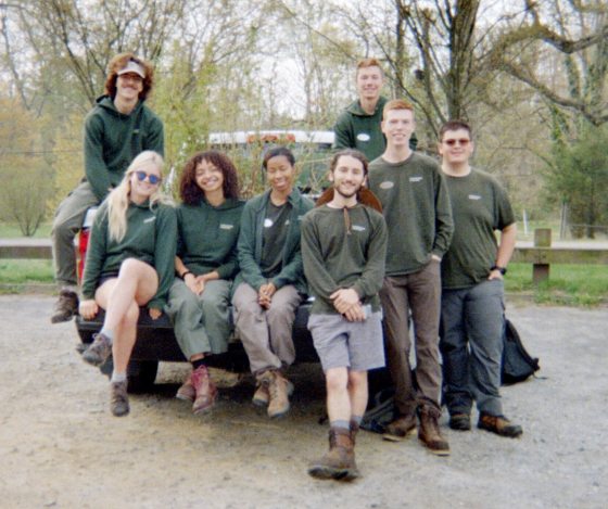 A group photo of eight Professional Horticulture students (Logon Kline, Rachael Adams, Melanie De La Cruz, Lauryn McMiller, Joshua Ferris, Micah High, Travis Cox, and Matthew Fleischhacker) sitting on the tailgate of a truck and standing in a gravel parking lot.