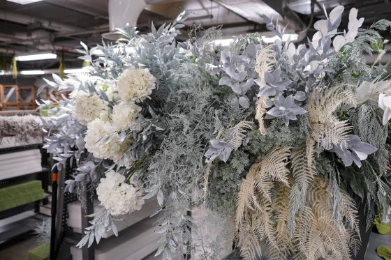 A floral arrangement featuring white and silver preserved flowers and grasses.