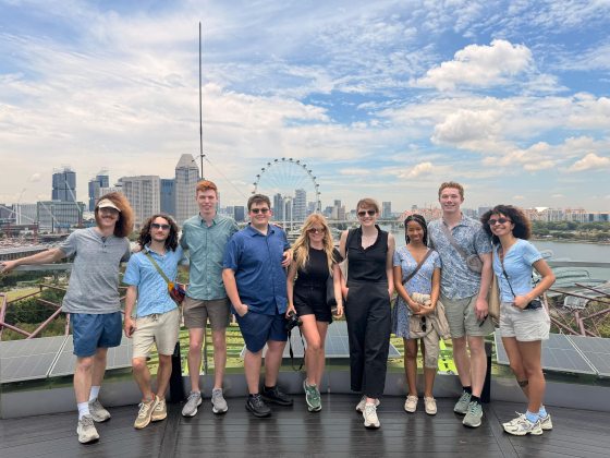 Nine students from the Professional Horticulture Program class of 2026—Logan Kline, Joshua Ferris, Travis Cox, Matthew Fleischhacker, Rachael Adams, Ellie Schlehr, Lauryn McMiller, Micah High, and Melanie De La Cruz—pose together at the Supertree Observatory in Singapore. Behind them, the city skyline, the Singapore Flyer, and a view of the waterfront are visible under a bright, partly cloudy sky.