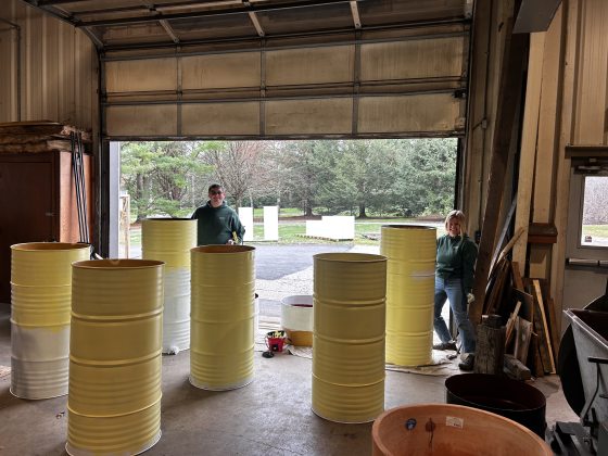 The inside of a large garage, featuring large yellow metal barralls. 