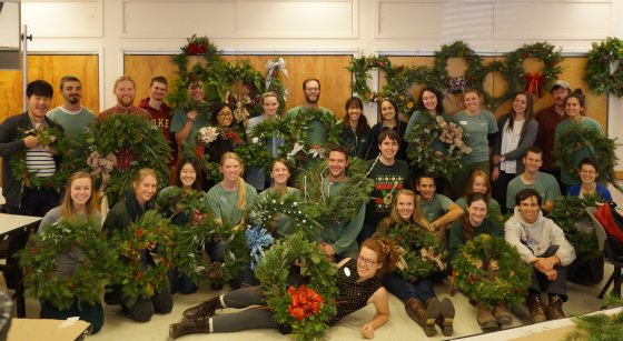a large group of people holding up homemade Christmas wreaths