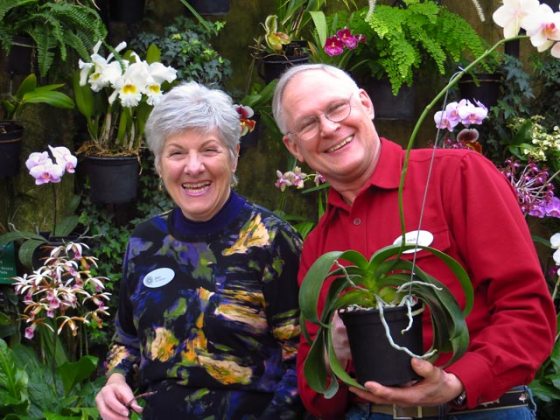 Two people holding orchids in the Orchid House