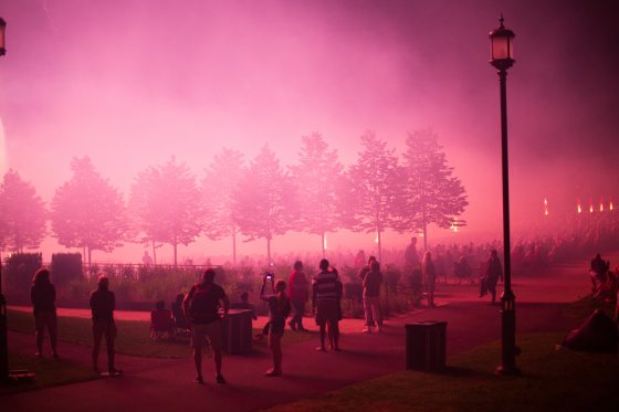 people standing admiring the main fountain garden show creating pink lights in the sky