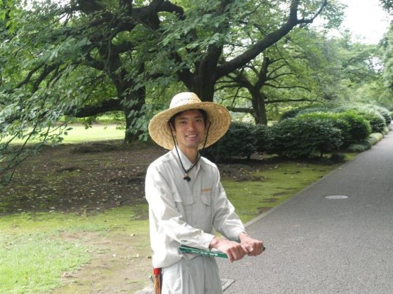 A man standing on a paved road with trees behind him in Japan