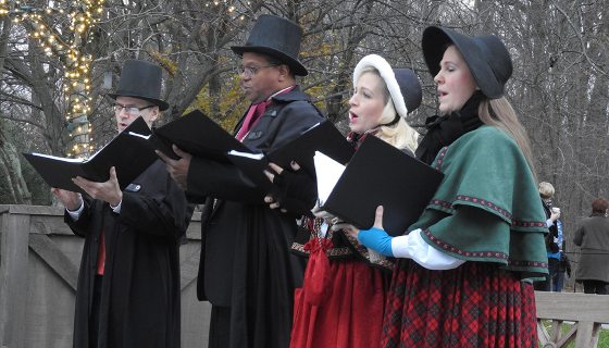 four people holding books and singing outside 