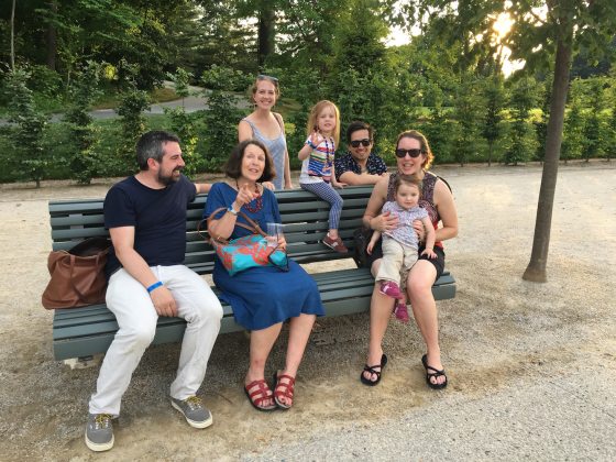 family sitting on one of the double-sided benches located at the Main Fountain Garden
