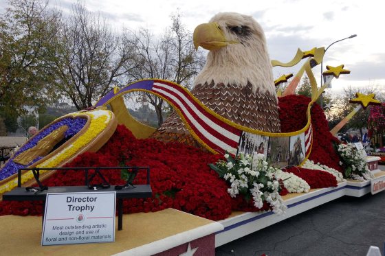 a floral float with a sculpture of a bald eagle surrounded by a blanket of red roses 