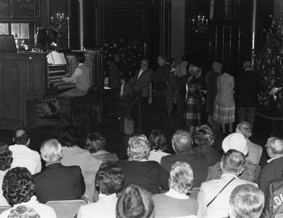 people sitting in an auditorium watching someone play the organ 