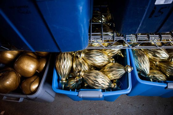 Three blue bins filled with shiny gold ornaments 
